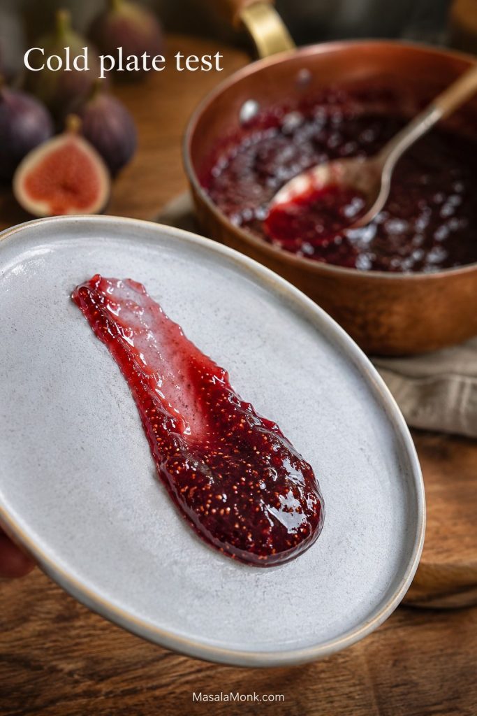 Spoonful of fig jam on a tilted chilled plate during a cold plate doneness test.