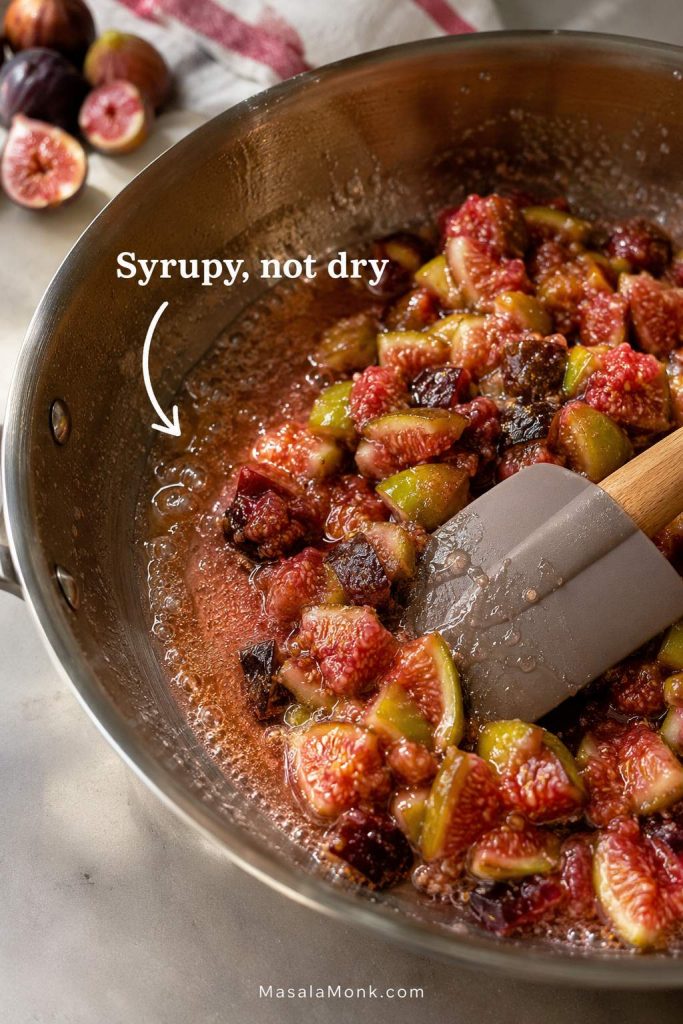 Chopped figs in a pan with syrupy edges forming as a spatula pulls through the mixture.