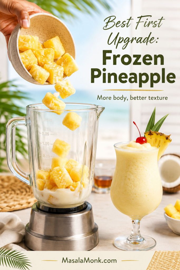 Frozen pineapple chunks being poured into a blender for a thicker pina colada, with a finished drink beside it.