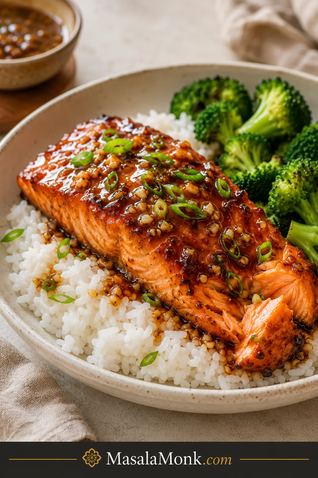 Honey garlic salmon served over white rice with broccoli in a shallow beige bowl.