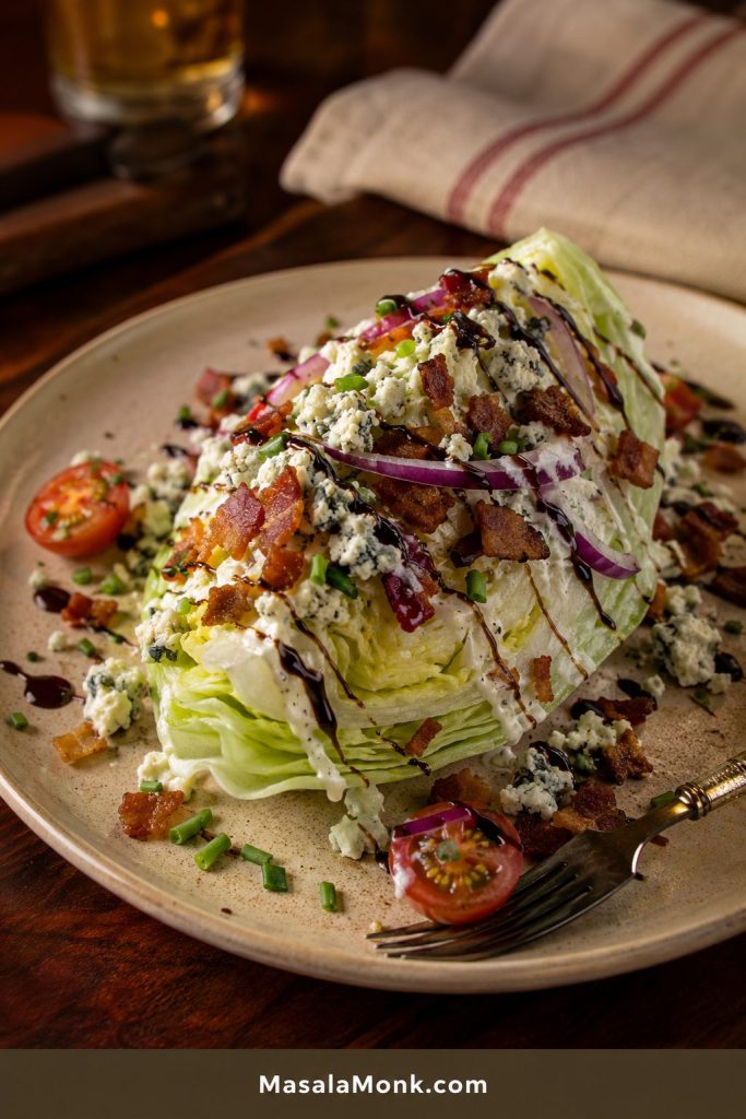 Outback-style iceberg wedge salad with blue cheese dressing, bacon, tomatoes, red onion, blue cheese crumbles, chives, and thin balsamic glaze lines.