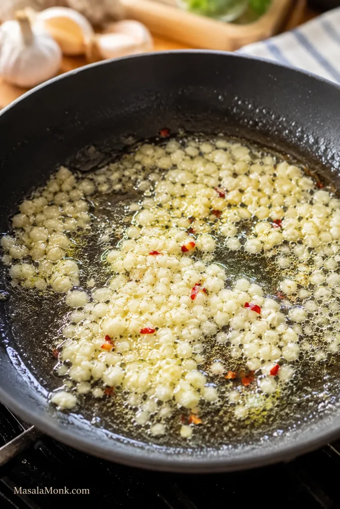 Pale minced garlic cooking gently in butter or olive oil with red pepper flakes.