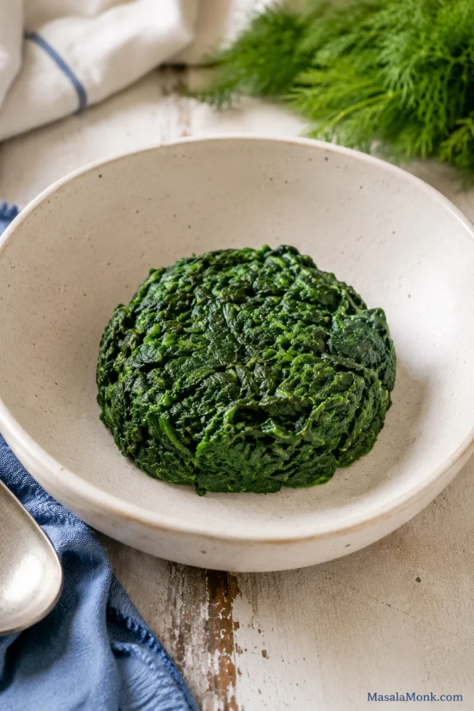 A compact mound of pressed spinach in a dry bowl with no visible liquid underneath.