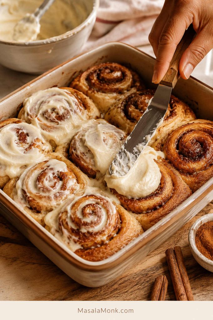Cream cheese icing spread over warm homemade cinnamon rolls