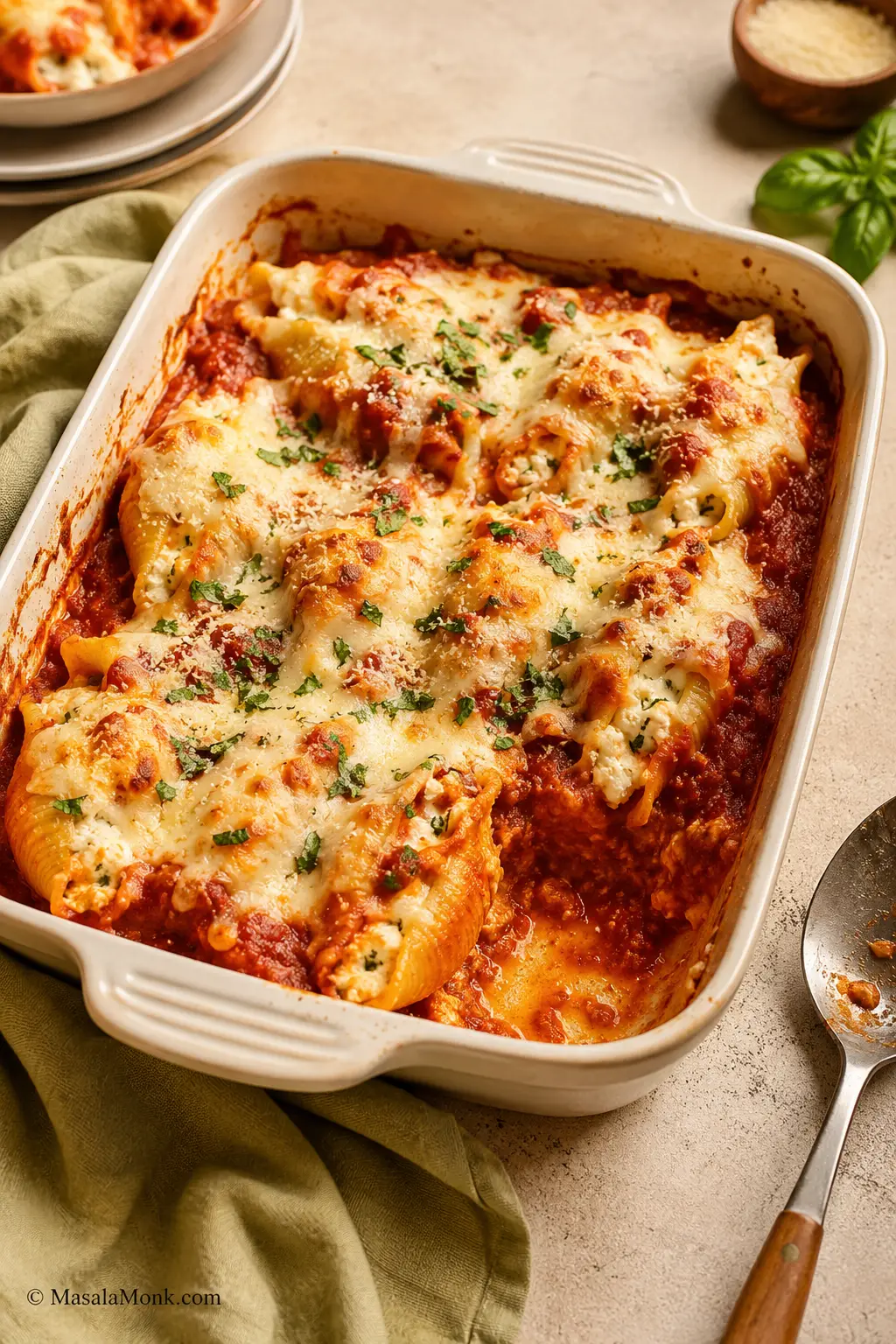 Baked ricotta stuffed shells with marinara sauce and melted mozzarella in a cream baking dish.