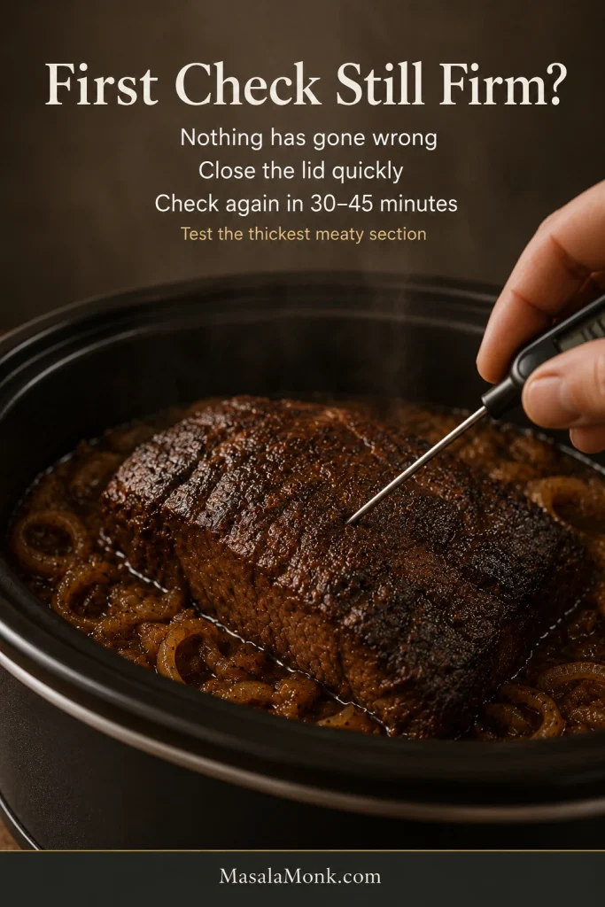 A thermometer probe entering the thickest center of browned brisket during an early tenderness check inside an onion-filled slow cooker.