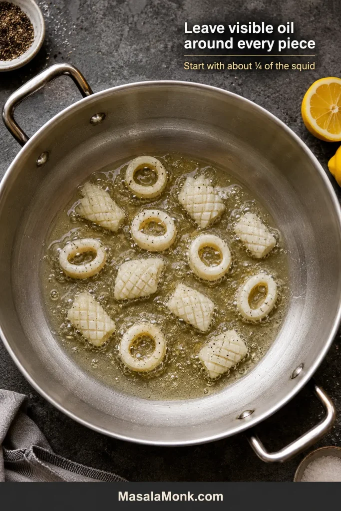 Small batch of squid frying with open oil space around each separate piece.
