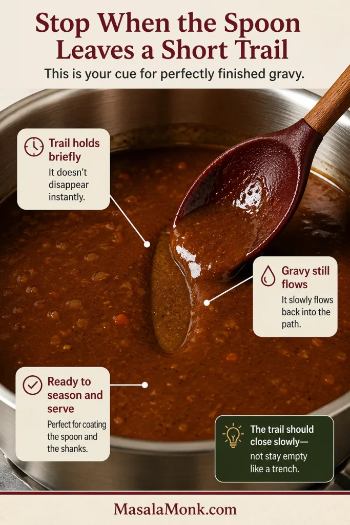 A spoon leaves a narrow trail through glossy brown gravy that begins to close slowly.