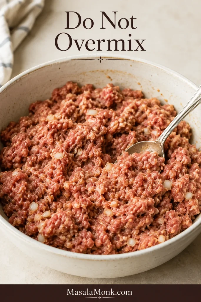 Ground beef mixture for Salisbury steak patties in a bowl with visible breadcrumbs and onion.