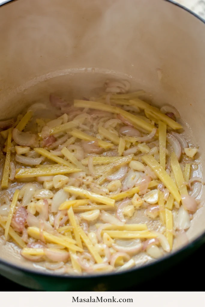 Sliced ginger, garlic, and onion sautéing in oil inside a pot for Chicken Tinola.