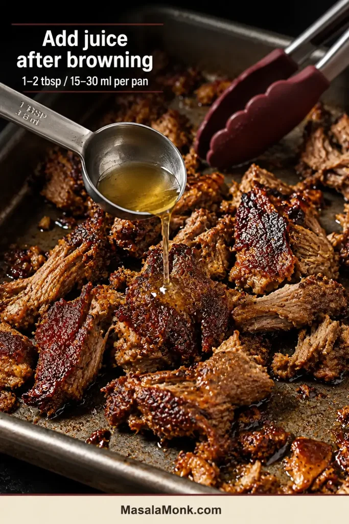 A measured tablespoon of reserved pork cooking juice is drizzled over carnitas after the meat has developed dark browned edges.