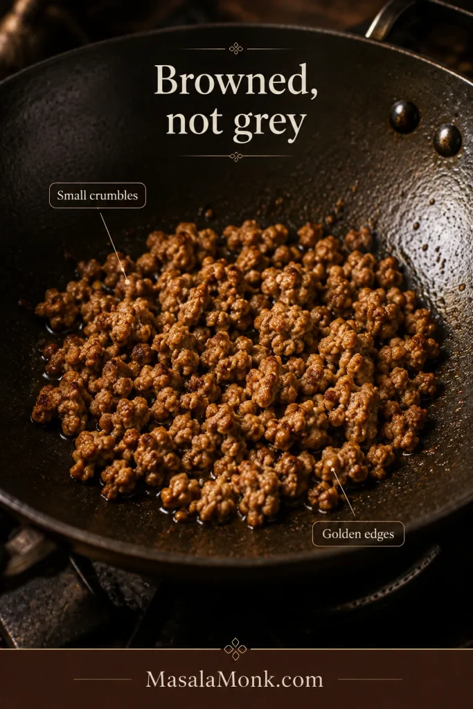 Small separated ground-pork crumbles browned in a dark wok, with golden edges and no visible pool of cooking liquid.