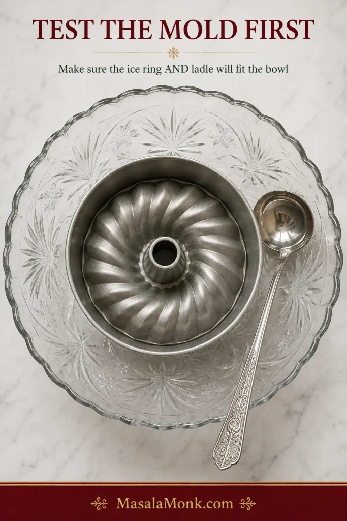 Overhead view of an empty Bundt pan placed inside an empty glass punch bowl with a ladle beside it to check that both will fit.