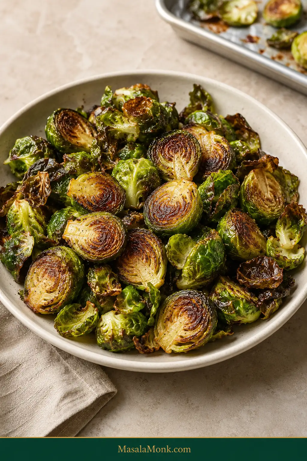 Cream bowl filled with roasted Brussels sprouts with mahogany-brown cut sides, crisp dark-green outer leaves and tender green centers.