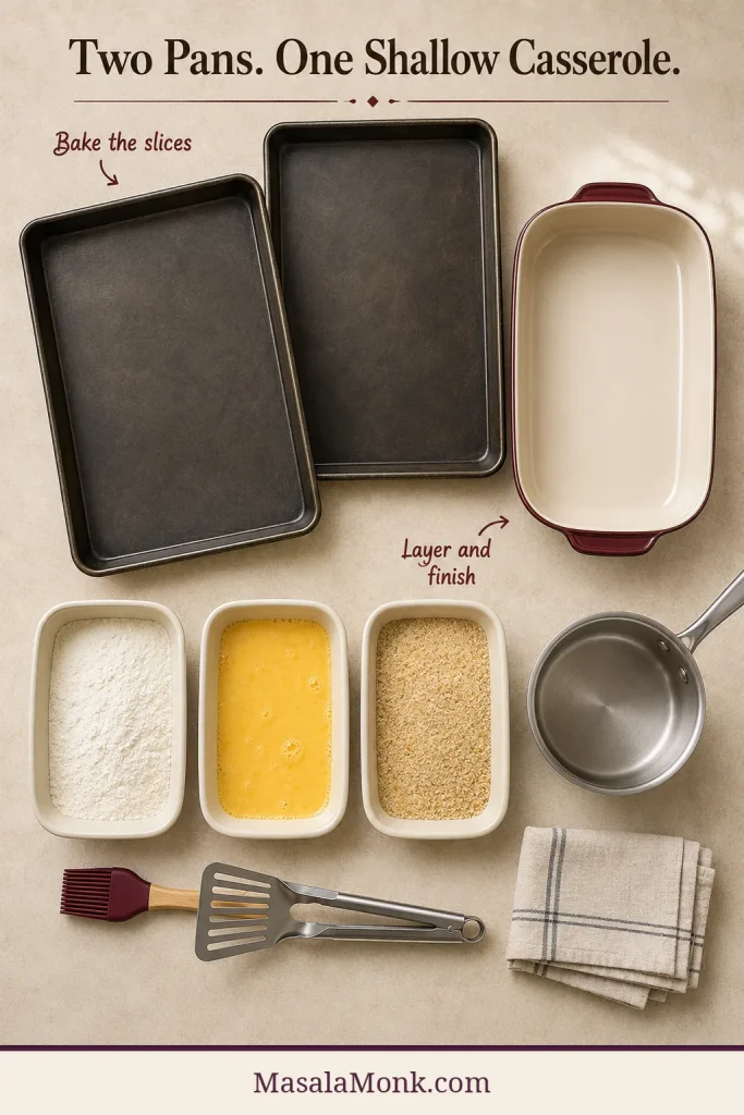 Two sheet pans, shallow burgundy casserole, breading dishes, saucepan, brush and spatula arranged on a counter.