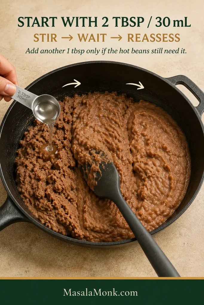 Measured liquid being added to refried beans with guidance to start with 2 tablespoons, stir, wait, and reassess.