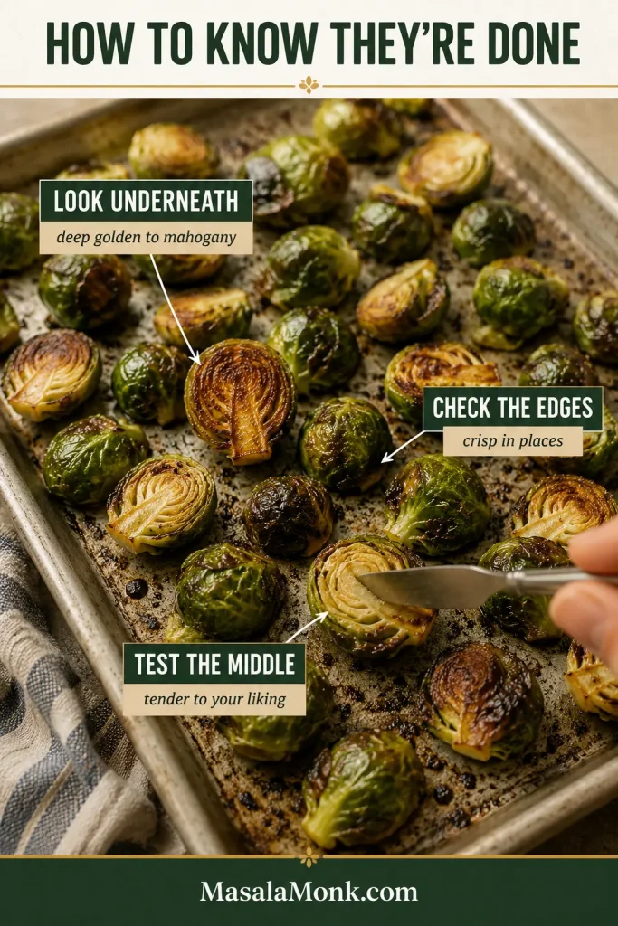 Roasted Brussels sprouts on a sheet pan with one piece turned over to show its browned underside and another being tested in the center with a utensil.