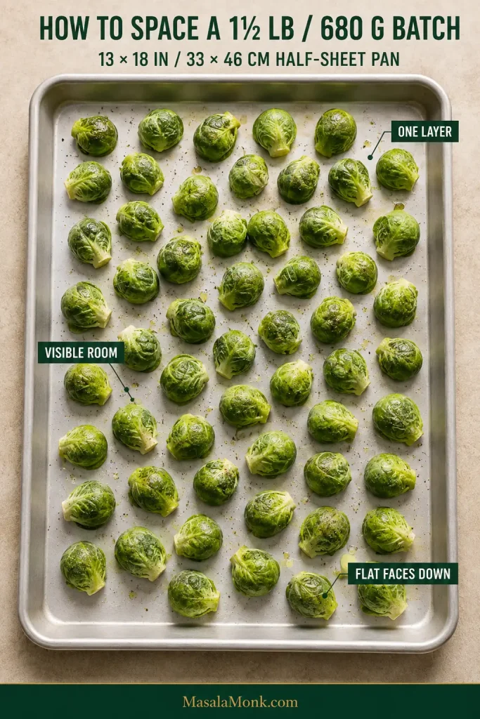 Overhead half-sheet pan with Brussels sprouts arranged in one uncrowded layer, leaving gaps between pieces and keeping flat cut sides against the metal.