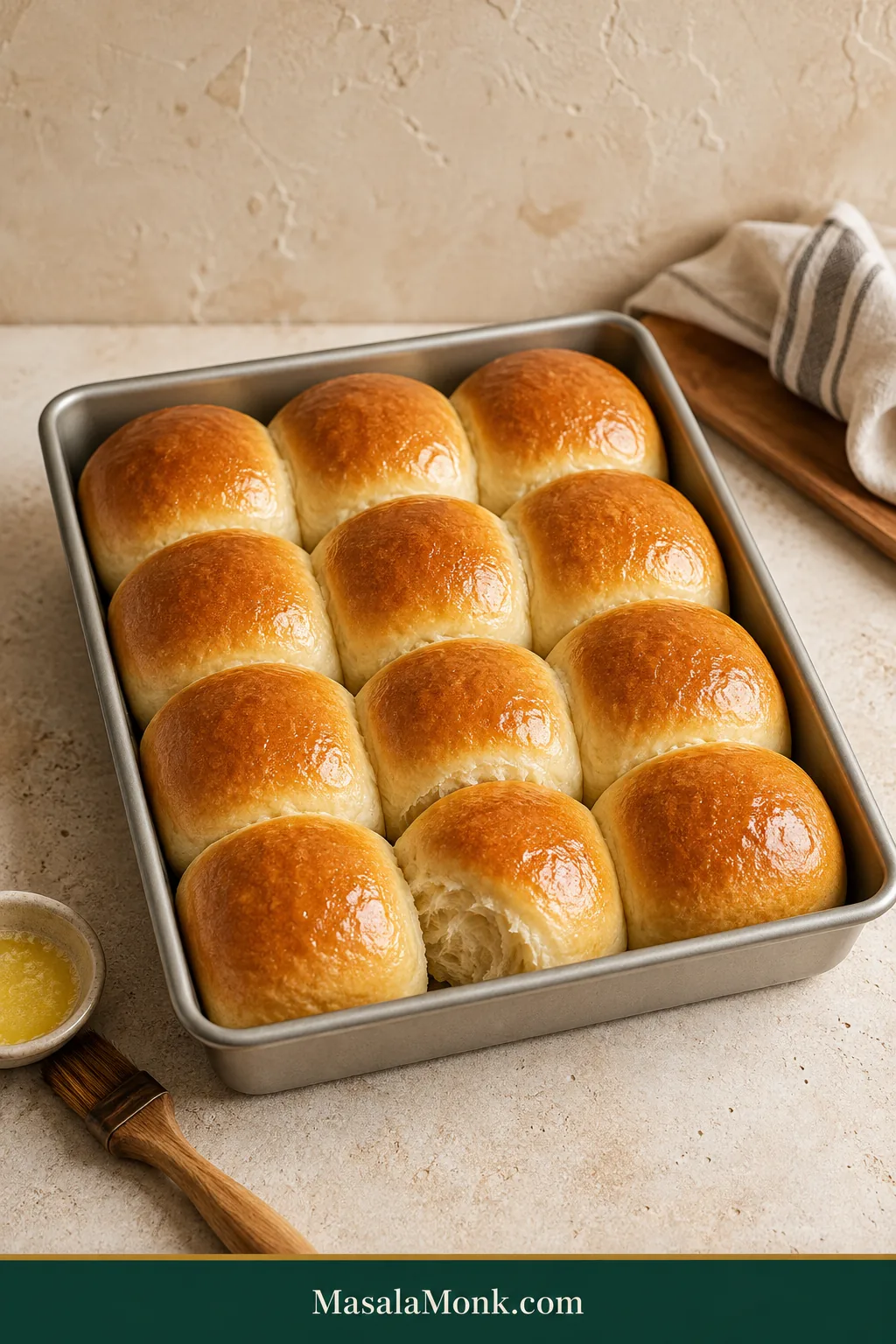 Twelve golden dinner rolls baked in four rows of three, with pale touching sides and one roll opened to show the soft interior.
