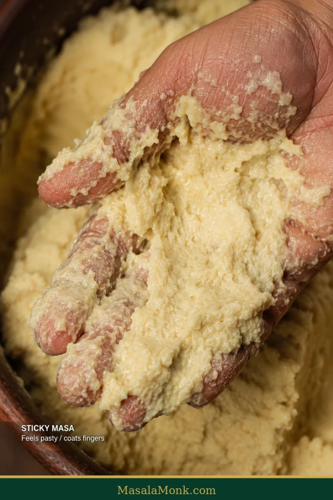 Very sticky corn tortilla masa coating a person's fingers with a wet, pasty texture.