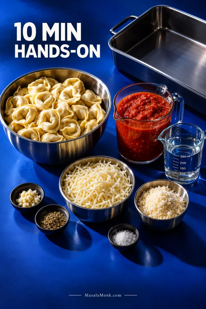 Refrigerated cheese tortellini, marinara, measured water, mozzarella, Parmesan and an empty metal baking dish arranged on a blue surface.