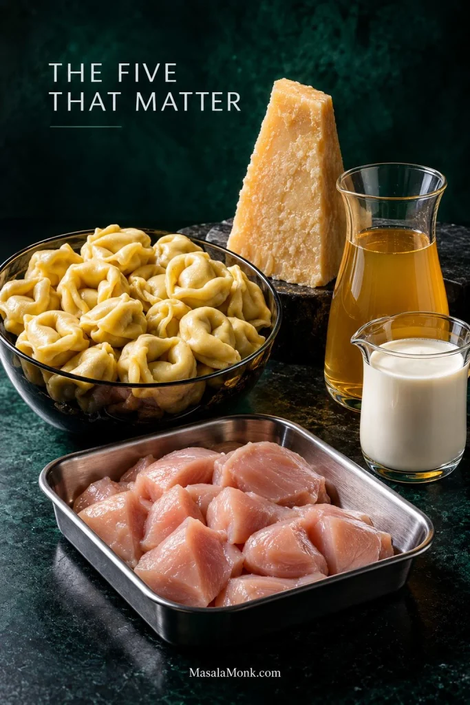 Raw chicken pieces, refrigerated cheese tortellini, chicken broth, heavy cream and a wedge of Parmesan arranged on dark surfaces.