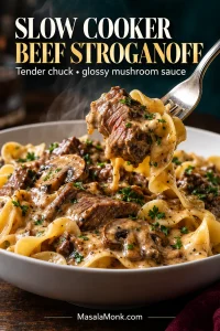 Close-up bowl of beef stroganoff with wide egg noodles, mushrooms and beef chunks, with a fork lifting a sauced bite.