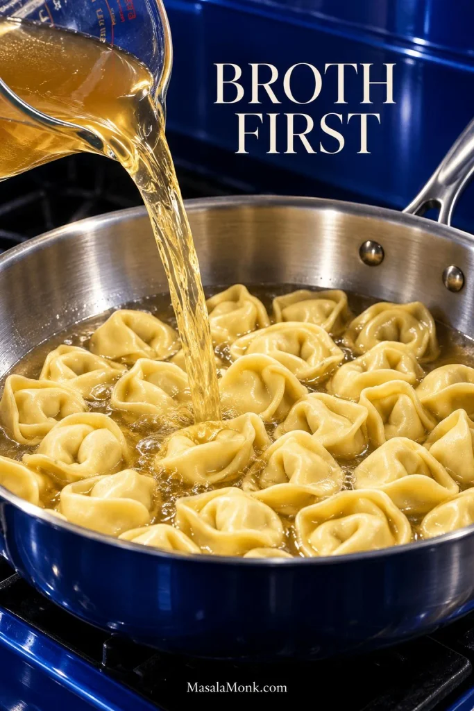 Golden chicken broth being poured into a skillet of uncooked cheese tortellini; text reads “Broth First.”