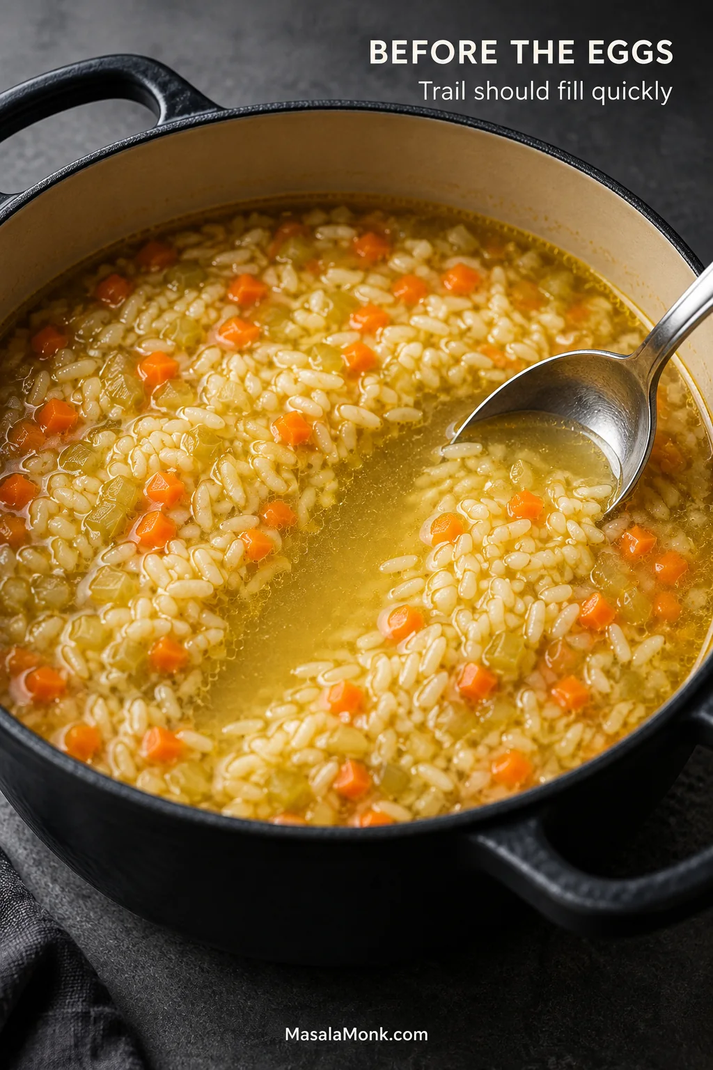 Spoon drawn through golden chicken-and-rice broth before the egg-lemon finish, leaving a temporary trail with liquid flowing back around the rice and vegetables.