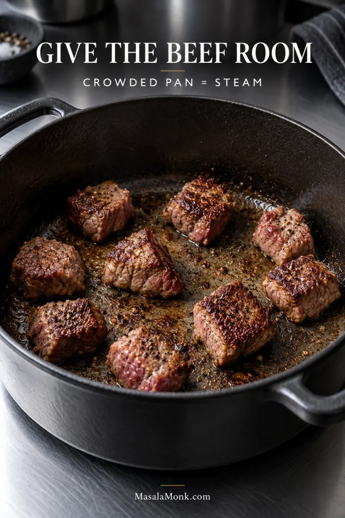 Chuck beef pieces spaced apart in a hot pan with visible cooking surface between them as the contact sides brown.
