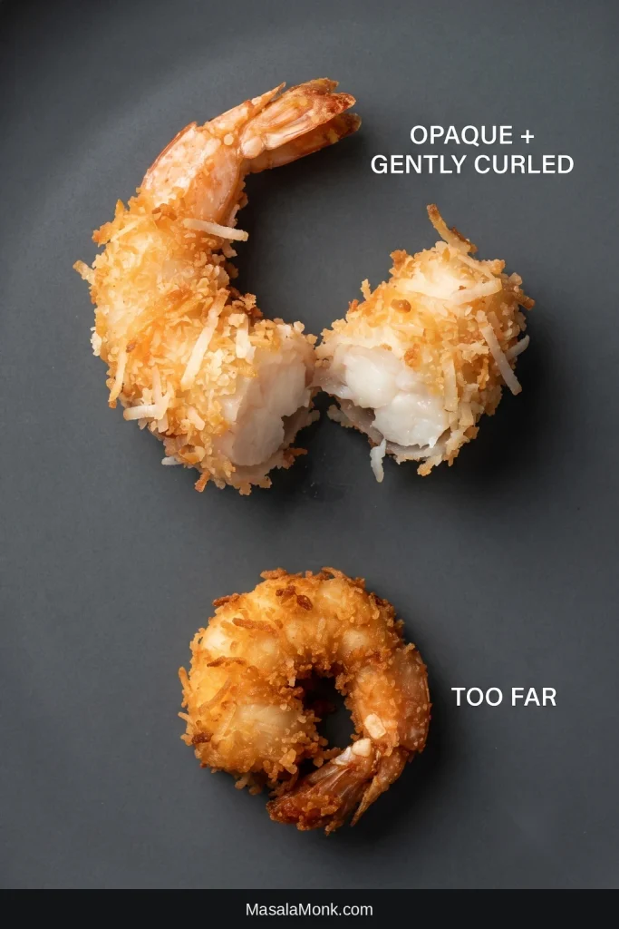 Two cooked coconut shrimp shown open to expose their centers, with one gently curled and opaque and the other tightly curled from overcooking.