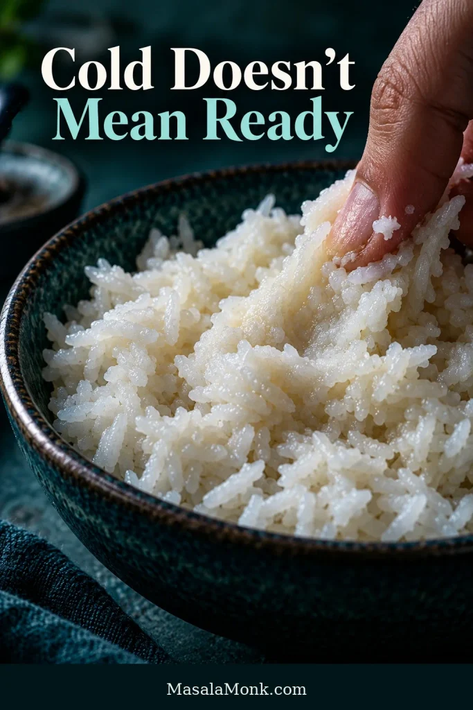 Fingers pressing chilled cooked rice that appears soft, moist and compacted instead of separating cleanly into individual grains.