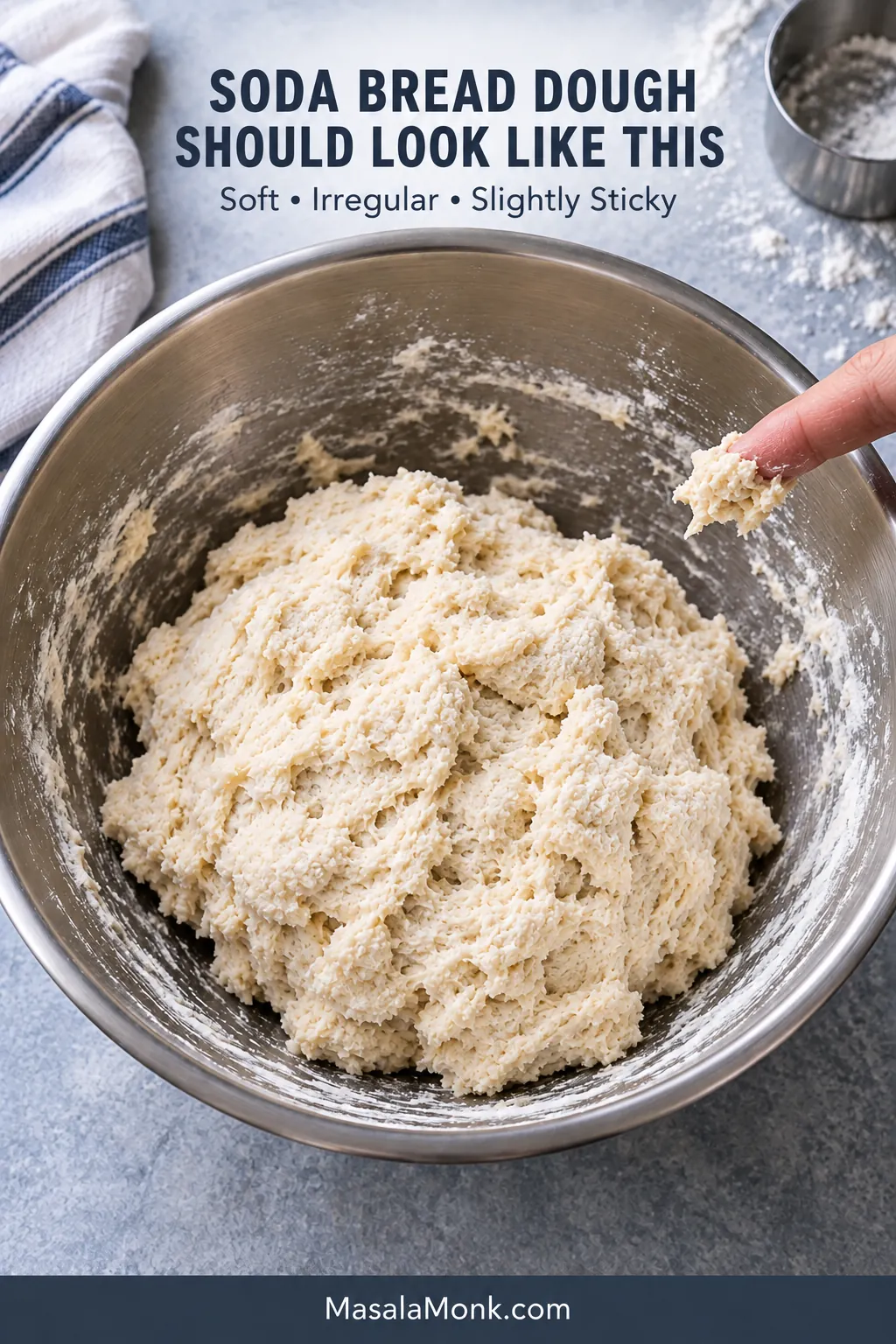 Shaggy, slightly sticky soda bread dough in a stainless-steel bowl, with a small piece of dough clinging to a fingertip.