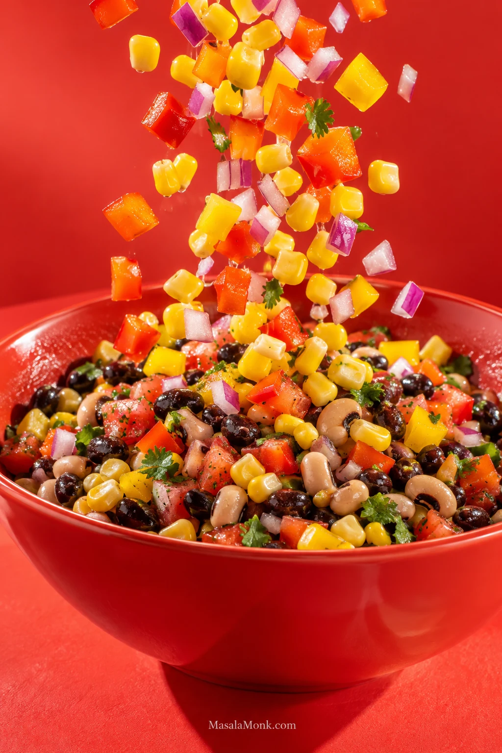 Fresh diced bell pepper, red onion and corn falling into Cowboy Caviar to add crisp texture back to a softer rested bowl.