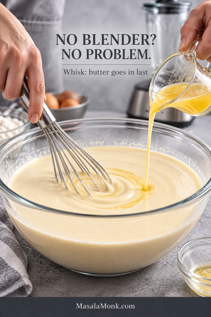 Hands whisking fluid crepe batter in a glass bowl while warm melted butter is poured from a small pitcher, with a blender in the background.