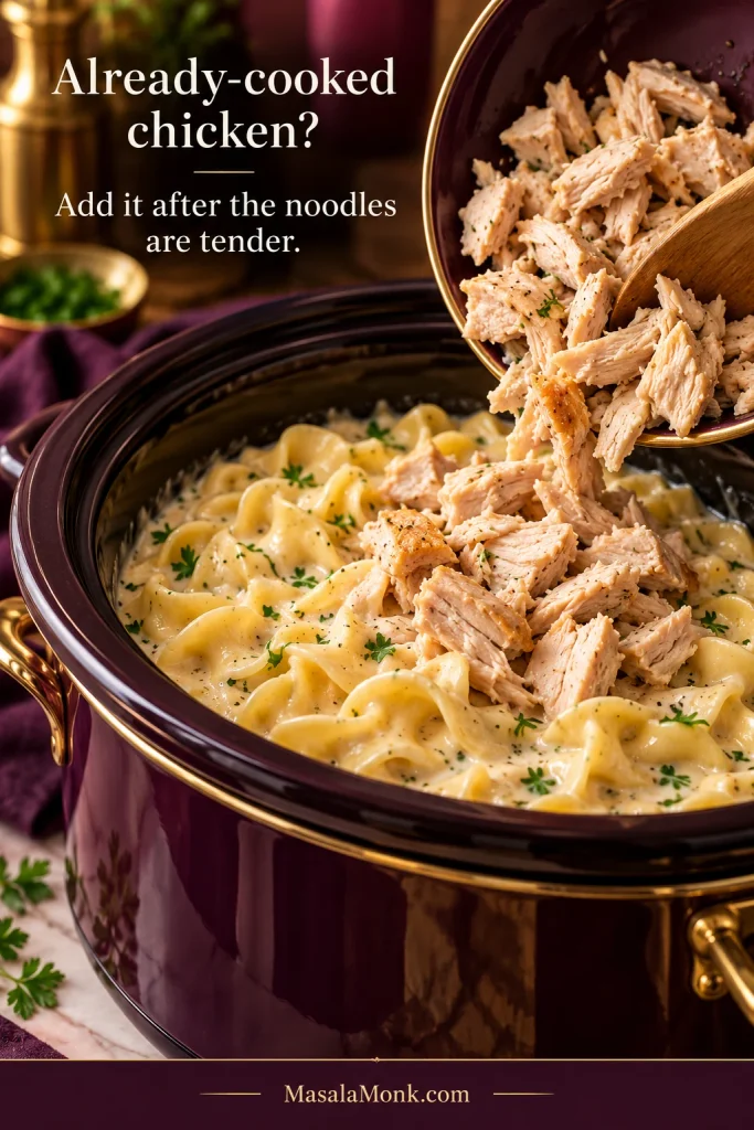 Cooked chicken pieces being added to creamy egg noodles in a slow cooker after the noodles have cooked.