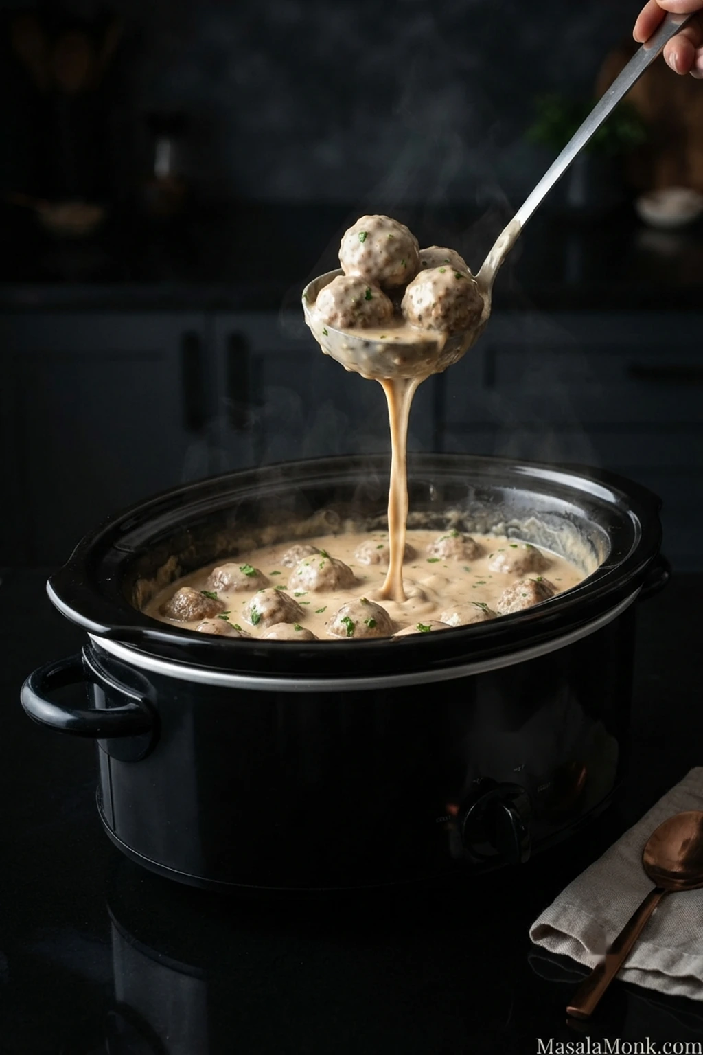 Creamy Crock Pot Swedish meatballs in an oval slow cooker, with a ladle lifting several meatballs as pale brown gravy drips back into the pot.