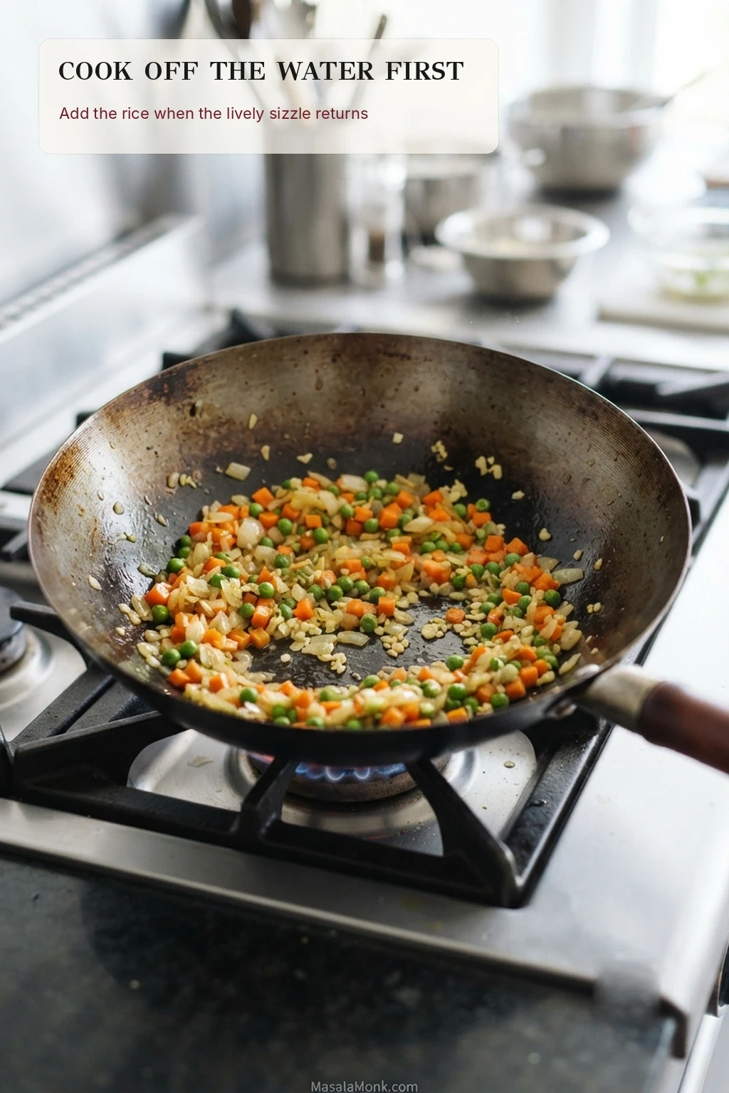 Diced carrots, peas, onion and aromatics sautéing in a wide wok with mostly dry exposed metal and no rice yet added.