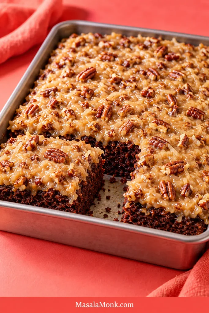 Rectangular chocolate cake in a 9-by-13-inch pan topped with coconut-pecan frosting, with portions removed to reveal the chocolate crumb.