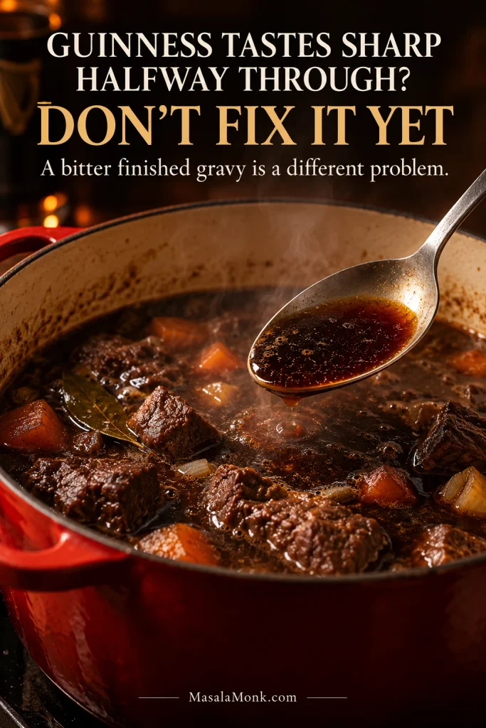 Spoon lifting dark braising liquid from a steaming Dutch oven while Guinness beef stew is still cooking.