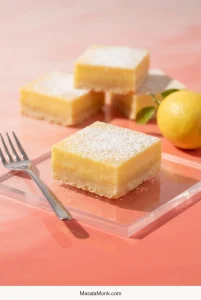 Finished lemon bars with smooth pale-yellow lemon filling over thin golden shortbread crusts, lightly dusted with powdered sugar.