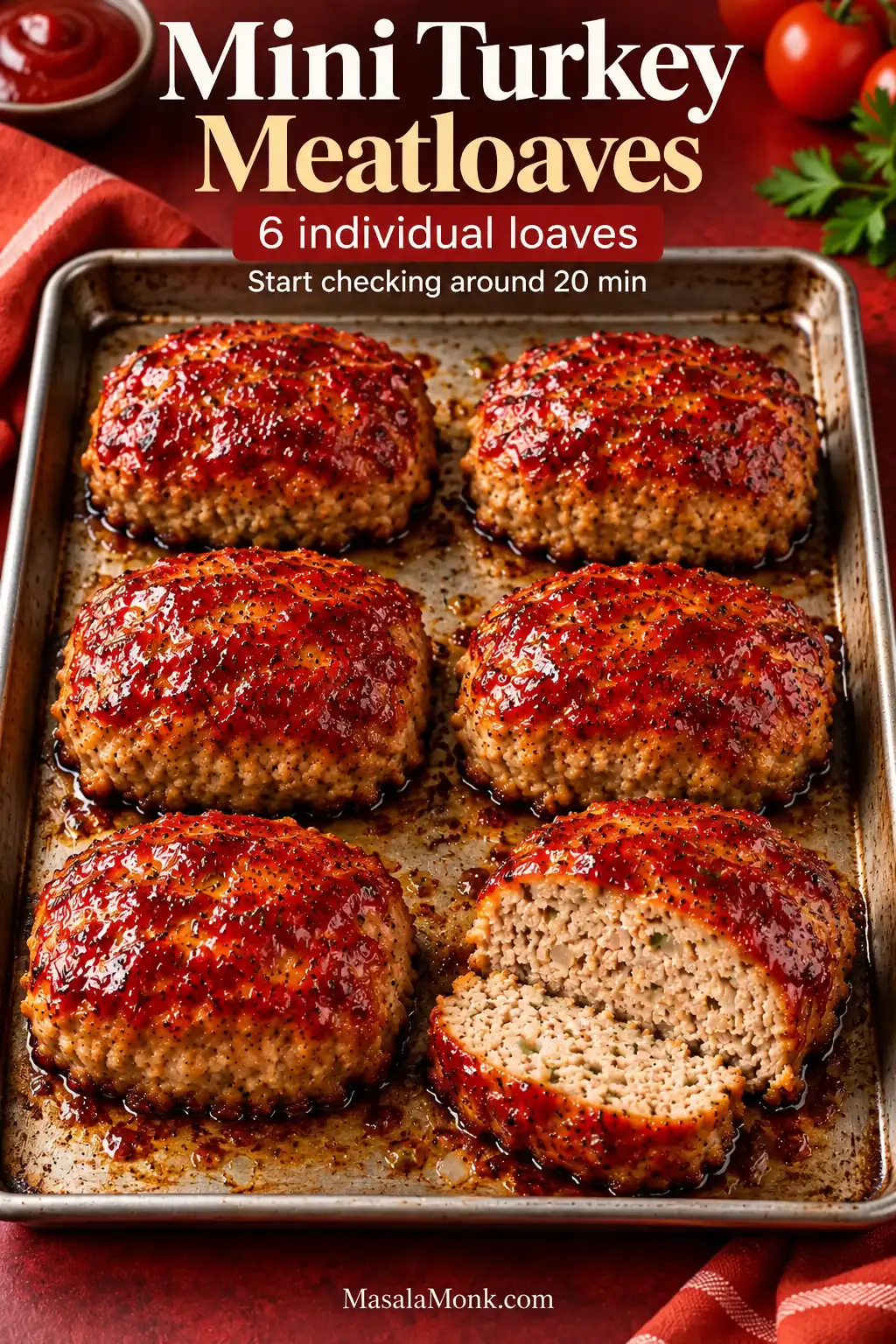 Six individually shaped glazed turkey meatloaves arranged on a rimmed baking sheet, with one cut open to reveal the cooked turkey interior.