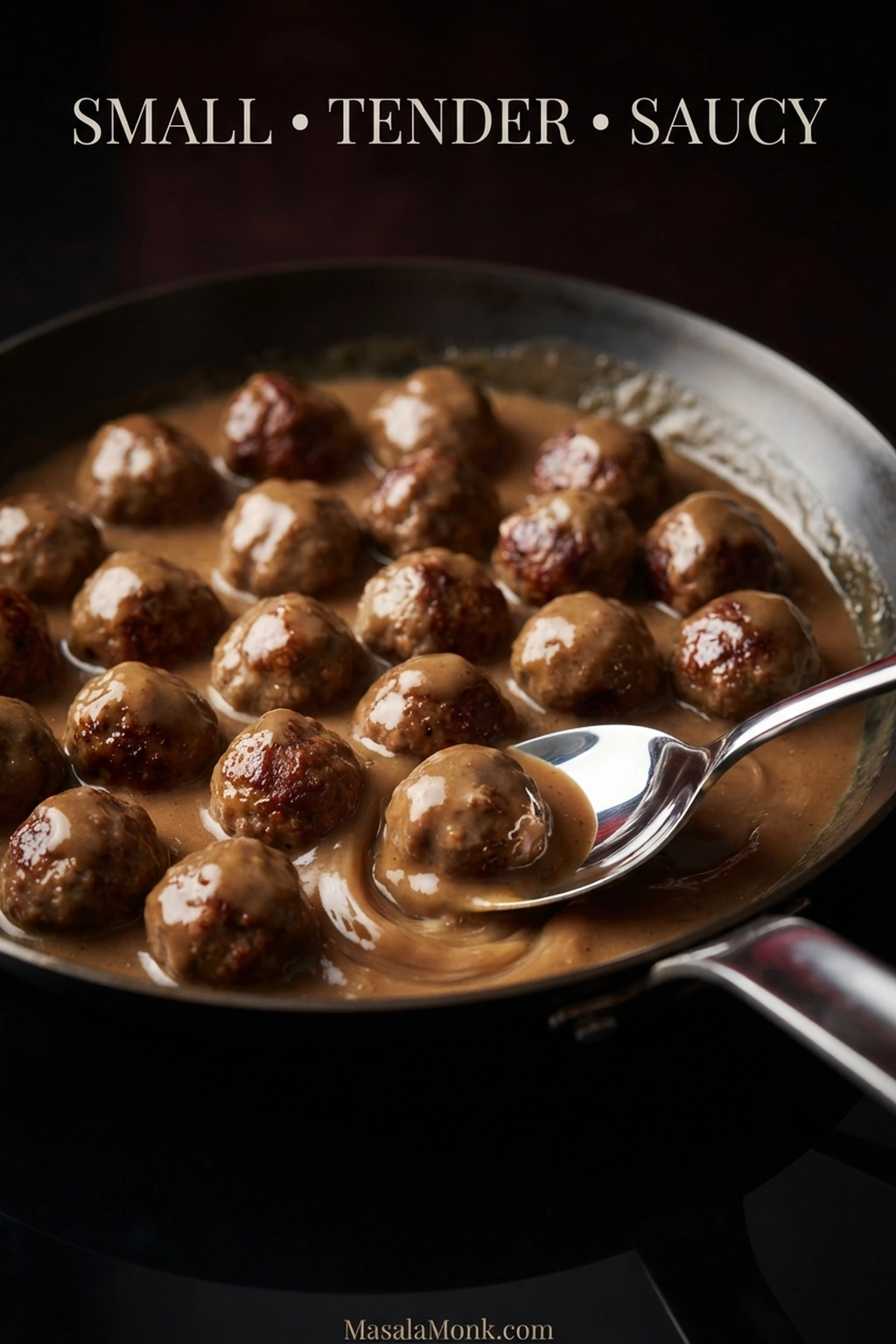 Skillet filled with small browned Swedish meatballs in creamy brown gravy, with patches of browned crust still visible.
